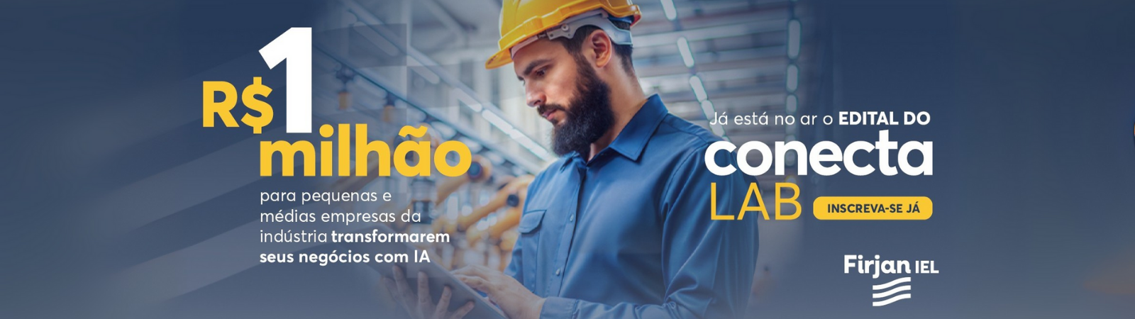 Profissional de capacete e uniforme azul utiliza um tablet em ambiente industrial com máquinas automatizadas ao fundo.